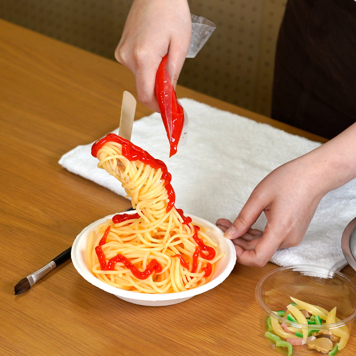 自分でつくる食品サンプルキット「さんぷるんvol.1 ナポリタン」の製作工程画像です。ゼラチンでできたトマトソースをかけています。