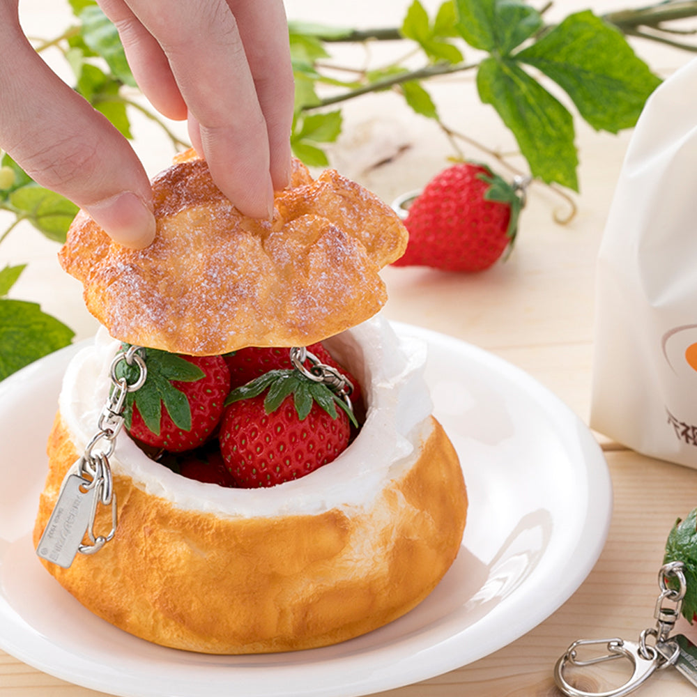 これは元祖食品サンプル屋の「シュークリーム 小物入れ」に「キーリング イチゴ」を入れた商品イメージ画像です。