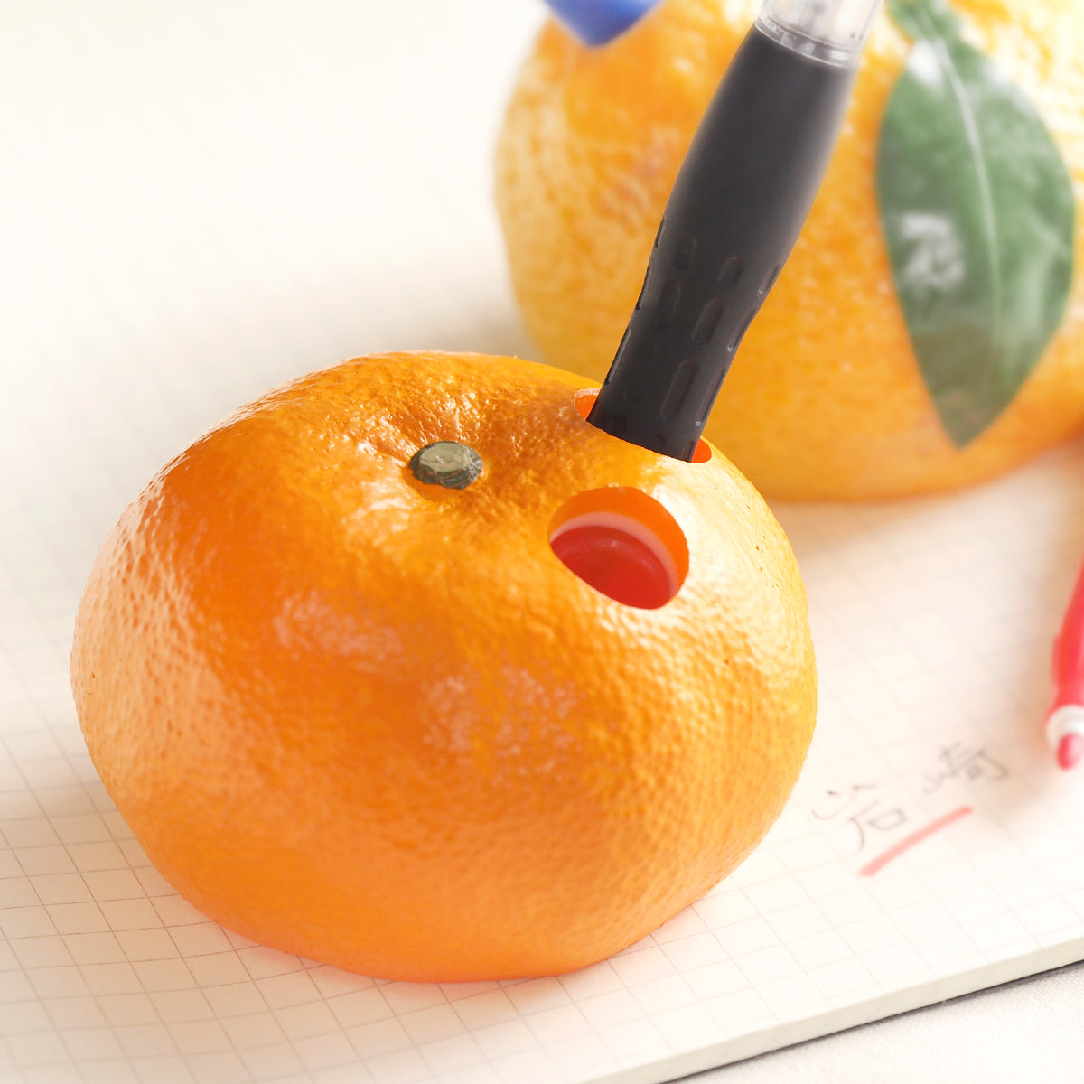 これは元祖食品サンプル屋の「みかん ペン立て」のペンを挿した商品使用イメージ画像です。